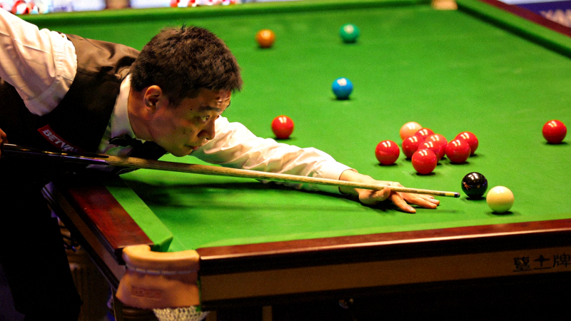 斯诺克世锦赛比赛场景，丁俊晖专注击球，台球桌上彩球位置清晰