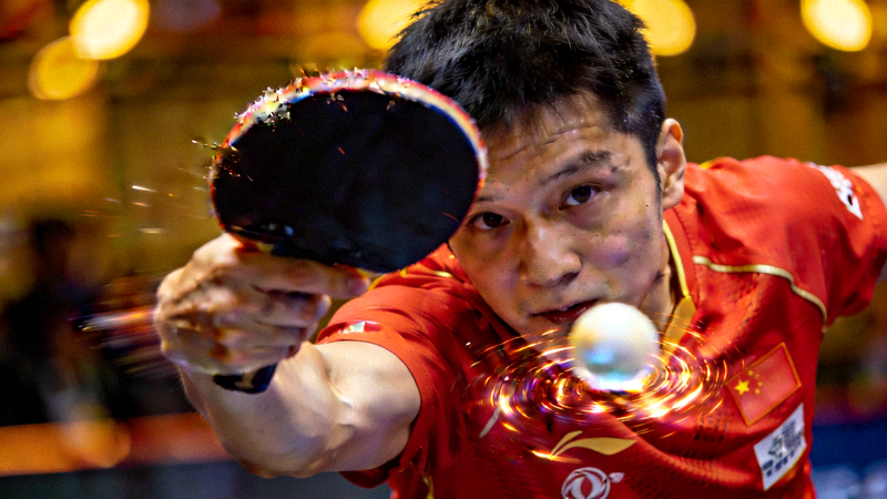 WTT乒乓球大满贯比赛现场，中国选手樊振东正手拉球瞬间特写