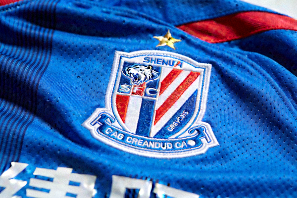 上海申花队蓝色主场球衣特写，队徽上的豹子头标志清晰可见